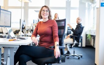 Mitarbeiterin sitzt an einem Schreibtisch in einem modernen Büro, das für Dokumentenmanagement genutzt wird.