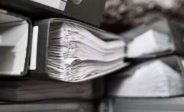 Ein Ordner mit vielen Dokumenten zeigt die revisionssichere Archivierung steuerrelevanter Dokumente für GoBD- und DSGVO-Konformität.