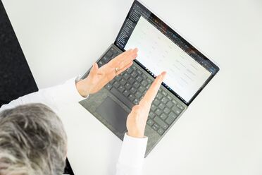 Eine Person zeigt auf einen Laptop-Bildschirm, auf dem eine Dokumentenmanagement-Software angezeigt wird.