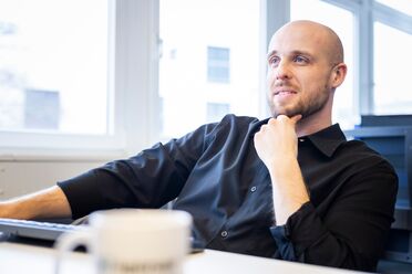 Ein Mitarbeiter sitzt am Schreibtisch und arbeitet mit einem Laptop, während ein Kaffeebecher auf dem Tisch steht. Dies zeigt eine Homeoffice-Lösung für effizientes und sicheres Arbeiten.