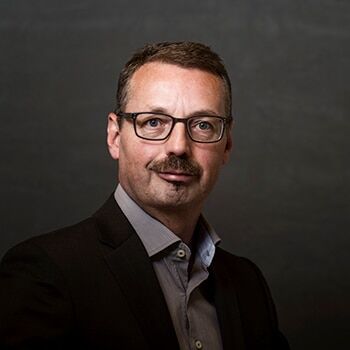 Jürg Rolli, Dipl. Wirtschaftsprüfer und Mitglied der Unternehmensleitung bei unico thun ag, steht vor einem dunklen Hintergrund und trägt ein Business-Outfit.