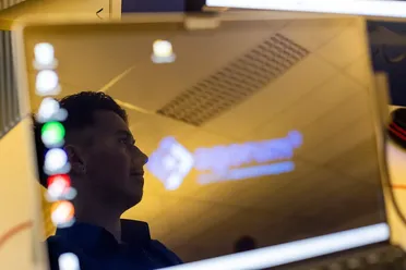 Raphael, Softwareentwickler, im Profil, spiegelt sich im Laptop-Bildschirm mit Logo. Fokus auf Digitalisierung und Entwicklung von Open Source DMS.