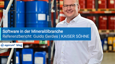 Ein Mitarbeiter von Kaiser Söhne steht in einem Lager mit blauen und roten Fässern, das digitale Dokumentenmanagement-System wird vorgestellt.