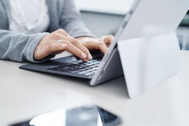 Eine Mitarbeiterin arbeitet am Laptop mit einem Dokumentenmanagement-System (DMS) für revisionssichere Archivierung.