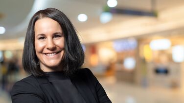 Anne Klein, CFO von agorum Software GmbH, steht in einem modernen Bürogebäude und lächelt.