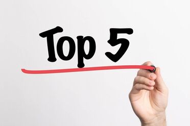 Eine Hand schreibt 'Top 5' auf eine weiße Tafel, um die beliebtesten Blogbeiträge des Jahres 2021 zu markieren.