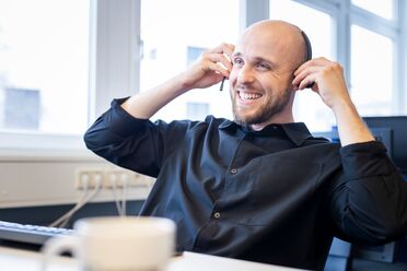 Ein Entwickler sitzt am Schreibtisch und passt das Open Source Dokumentenmanagement-System an individuelle Bedürfnisse an.