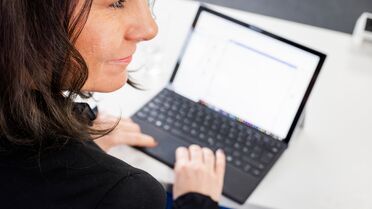 Mitarbeiterin arbeitet an einem Laptop mit der Dokumentation des Open Source DMS agorum core.