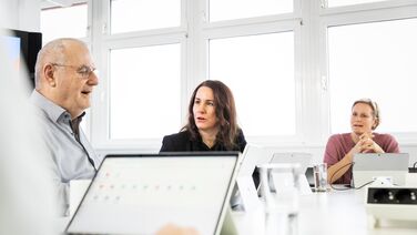 Team-Meeting zeigt Mitarbeiter, die am Tisch sitzen und an einem Dokumentenmanagement-System arbeiten