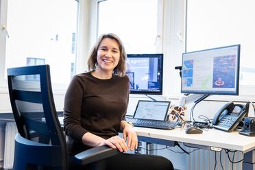 Ein Mitarbeiter sitzt am Schreibtisch und nutzt das digitale Vertragsmanagement-System mit mehreren Monitoren, die Vertragsübersichten anzeigen.