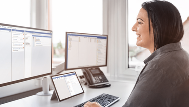 Mitarbeiterin arbeitet an mehreren Monitoren mit dem agorum core Interface, zeigt digitalen Workplace.