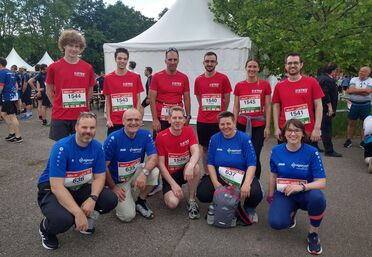 Teilnehmer des Firmenlaufs 2022 tragen Shirts von agorum und ETES, stehen vor einem Zelt und bereiten sich auf den Lauf vor.
