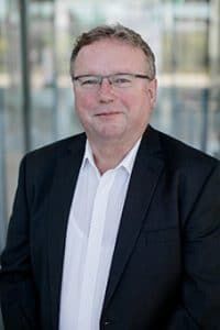Bernhard Margos, Geschäftsführer der Bechtle GmbH IT-Systemhaus Solingen, steht vor einem modernen Glasgebäude.