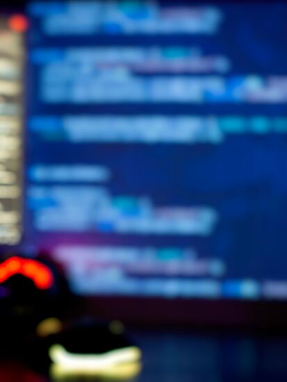 Ein Laptop zeigt eine Entwicklungsumgebung für ein Open Source DMS, im Hintergrund sind weitere Bildschirme mit Code zu sehen.