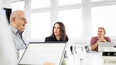 Team-Meeting zeigt Mitarbeiter, die am Tisch sitzen und an einem Dokumentenmanagement-System arbeiten