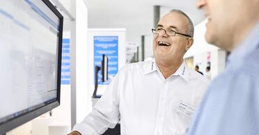 Ein Mitarbeiter von ACP Digital Business Solutions zeigt auf einem Bildschirm das Dokumentenmanagement-System.