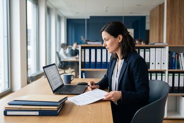 Fachkraft prüft einen Vertrag am Laptop mit zentraler Vertragsakte im digitalen Vertragsmanagement