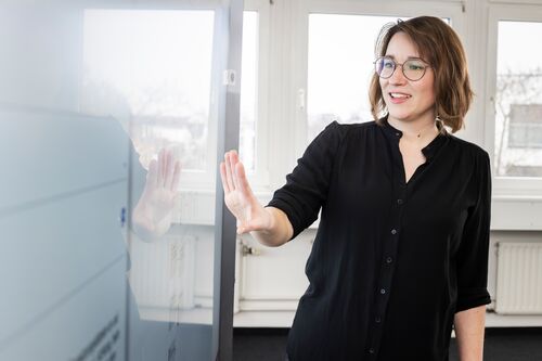 Eine Mitarbeiterin präsentiert das digitale Toolkit an einem interaktiven Whiteboard im Büro.