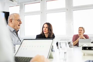 Team-Meeting zeigt Mitarbeiter, die am Tisch sitzen und an einem Dokumentenmanagement-System arbeiten