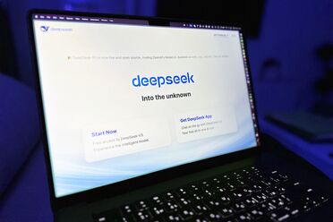 Bildschirmfoto zeigt die Webseite von DeepSeek-R1 mit der Aufforderung 'Start Now' und 'Get DeepSeek App' auf einem Laptop.