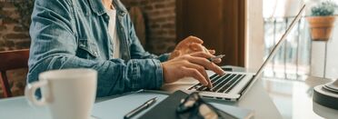 Person arbeitet im Homeoffice an einem Laptop, nutzt Dokumentenmanagement-Software für effizientes Arbeiten.