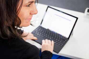 Mitarbeiterin arbeitet an einem Laptop mit der Dokumentation des Open Source DMS agorum core.