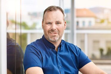 Oliver Schulze sitzt in einem Büro und spricht über Dokumentenmanagement und Digitalisierung.