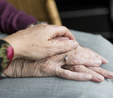 Eine Hand einer Pflegekraft hält die Hand einer seniorin, was die Unterstützung im Dokumentenmanagement für ambulante Pflege darstellt.