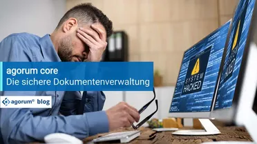 Ein Mitarbeiter mit Kopfschmerzen blickt auf einen gehackten Computer. Datenverlust und Sicherheitslücken bedrohen die Geschäftsprozesse und die Digitalisierung im Unternehmen.