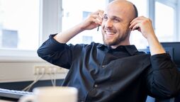 Ein Entwickler sitzt am Schreibtisch und passt das Open Source Dokumentenmanagement-System an individuelle Bedürfnisse an.