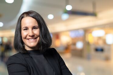 Anne Klein, CFO von agorum Software GmbH, steht in einem modernen Bürogebäude und lächelt.