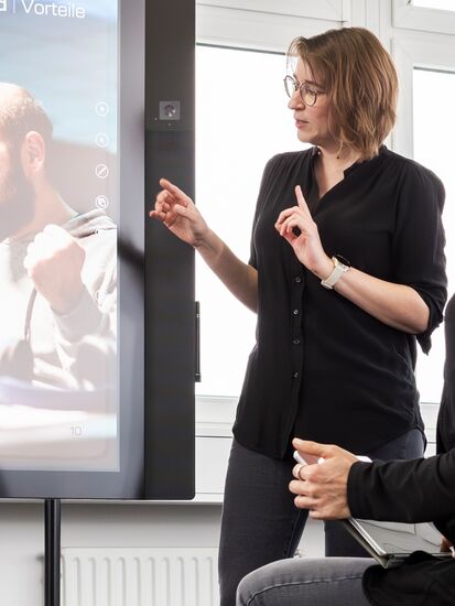 Eine Mitarbeiterin präsentiert vor Kollegen die Vorteile und Einsatzmöglichkeiten des DIGITAL TOOLKIT im Rahmen einer Bewerbung.