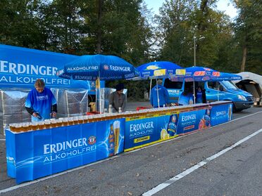 Erdinger Stand mit alkoholfreien Getränken beim Firmenlauf Stuttgart 2021, Mitarbeiter bedienen die Teilnehmer.
