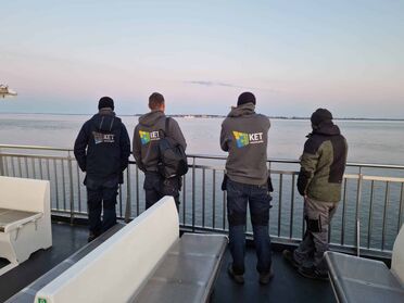 Mitarbeiter der Küstenhaus Energie Technik GmbH stehen auf einem Schiff und blicken auf das Meer in Schleswig-Holstein.