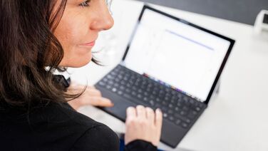 Mitarbeiterin arbeitet an einem Laptop mit der Dokumentation des Open Source DMS agorum core.
