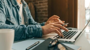 Person arbeitet im Homeoffice an einem Laptop, nutzt Dokumentenmanagement-Software für effizientes Arbeiten.