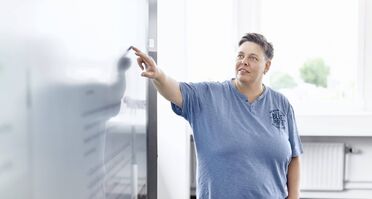 Ein Mitarbeiter zeigt auf ein Whiteboard, das den Backup-Prozess des Dokumentenmanagement-Systems erklärt.