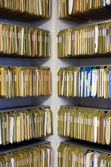 Regale voller Ordner zeigen die physische Speicherung von Personalakten vor der Digitalisierung im Dokumentenmanagement.